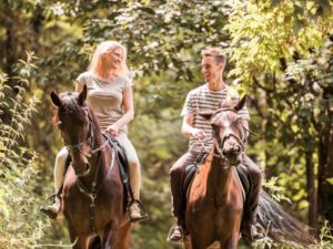 Couple Horseback Safaris surrounded by African wildlife and lush scenery.