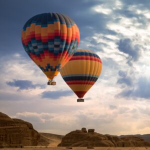 Hot air balloon soaring over the red dunes of the Namib Desert at sunrise